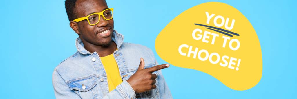 Image showing a man wearing yellow glasses and t-shirt with a blue jean jacket. He is pointing at the words 'You get to choose' in white letters on a yellow organic shape. The 'You' is underlined.